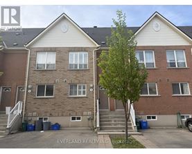 A tree stands in front of a two-story brick apartment building.