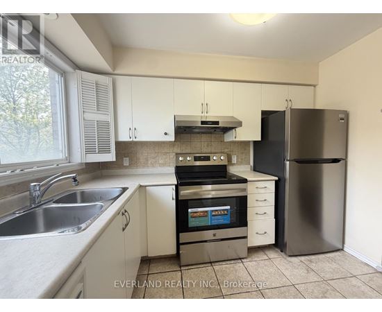 A kitchen with white cabinets and a stainless steel refrigerator.