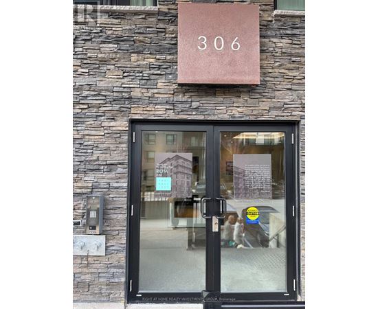 The door of a building with a glass window and a sign that says "306" above it.