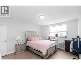 A bedroom with a bed, nightstand, and window.