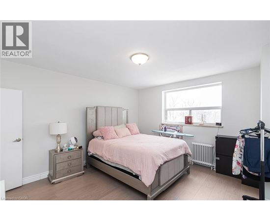 A bedroom with a bed, nightstand, and window.
