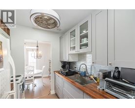 A well-lit kitchen with white cabinets and a wooden countertop.