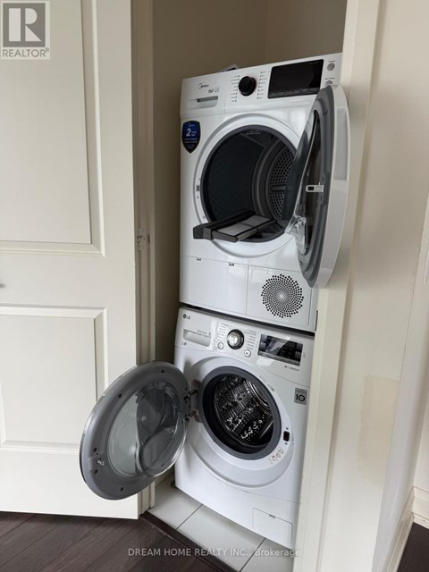 A white washing machine is in a small space next to a door.