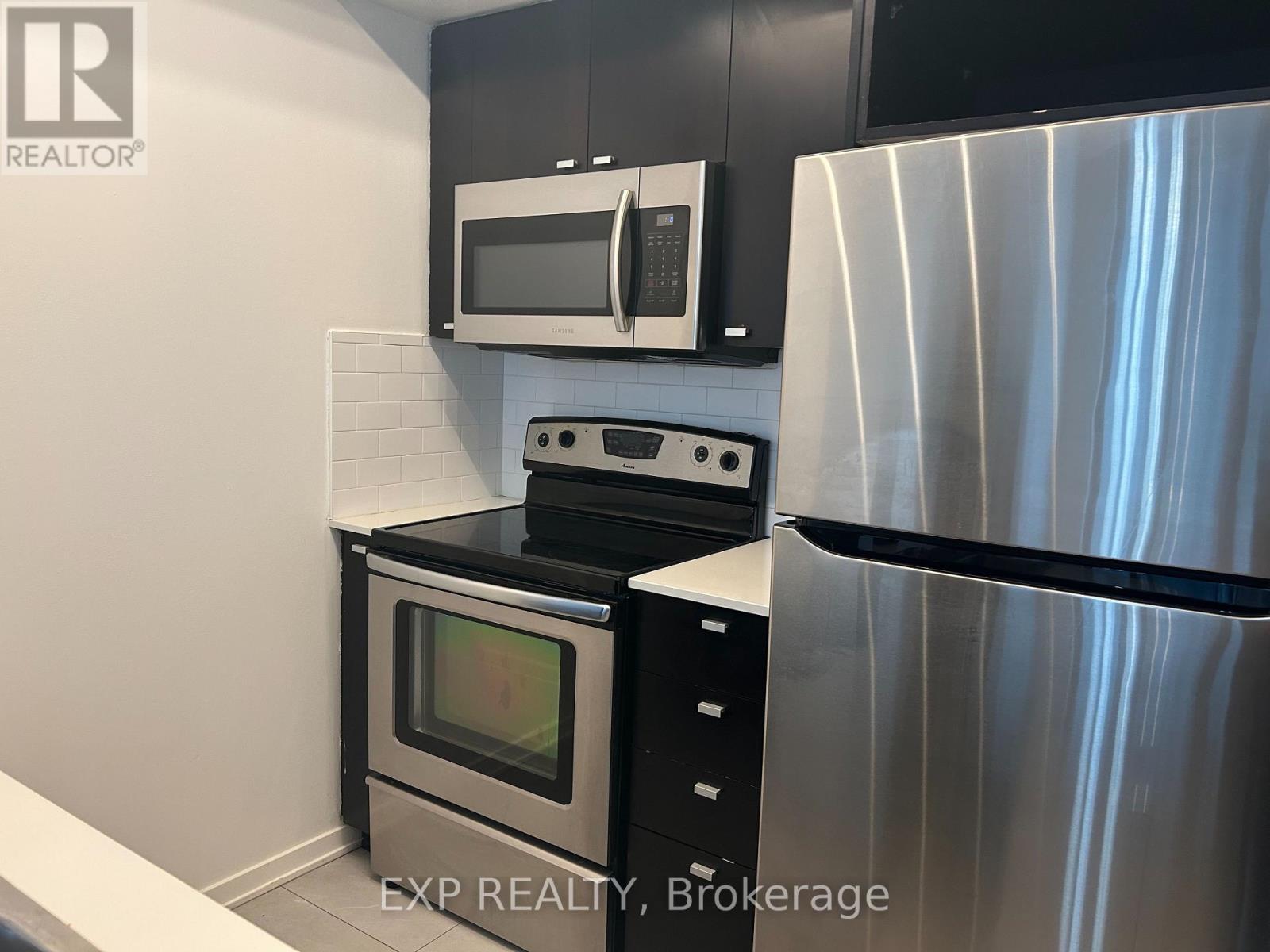 A modern kitchen with a stainless steel refrigerator, microwave, and oven.