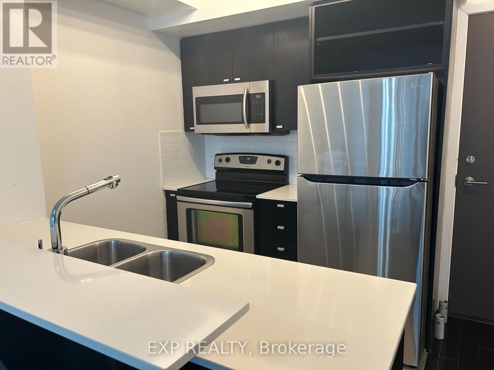 A kitchen with a sink, stove, and refrigerator.