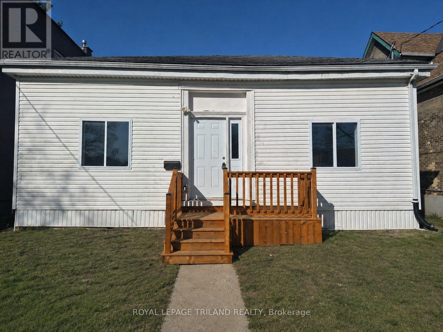 A white house with a wooden staircase leading to the front door.