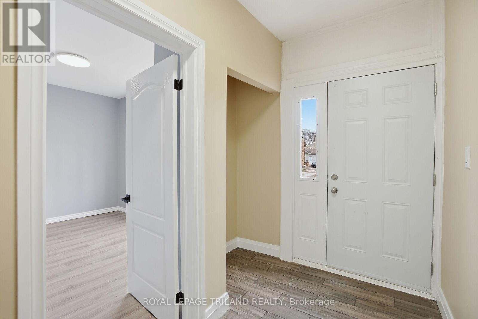 A white door is open to a hallway with a white door at the end of the hall.