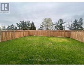A backyard with a wooden fence and green grass.