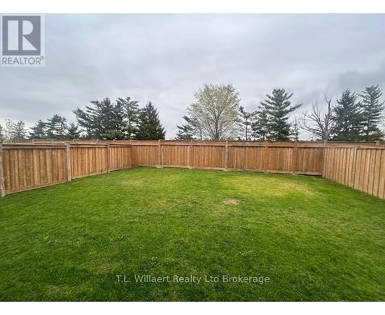 A backyard with a wooden fence and green grass.