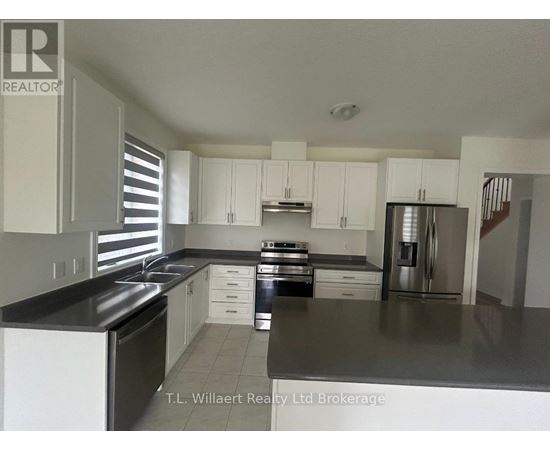 A kitchen with white cabinets and black countertops.