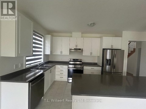 A kitchen with white cabinets and black countertops.