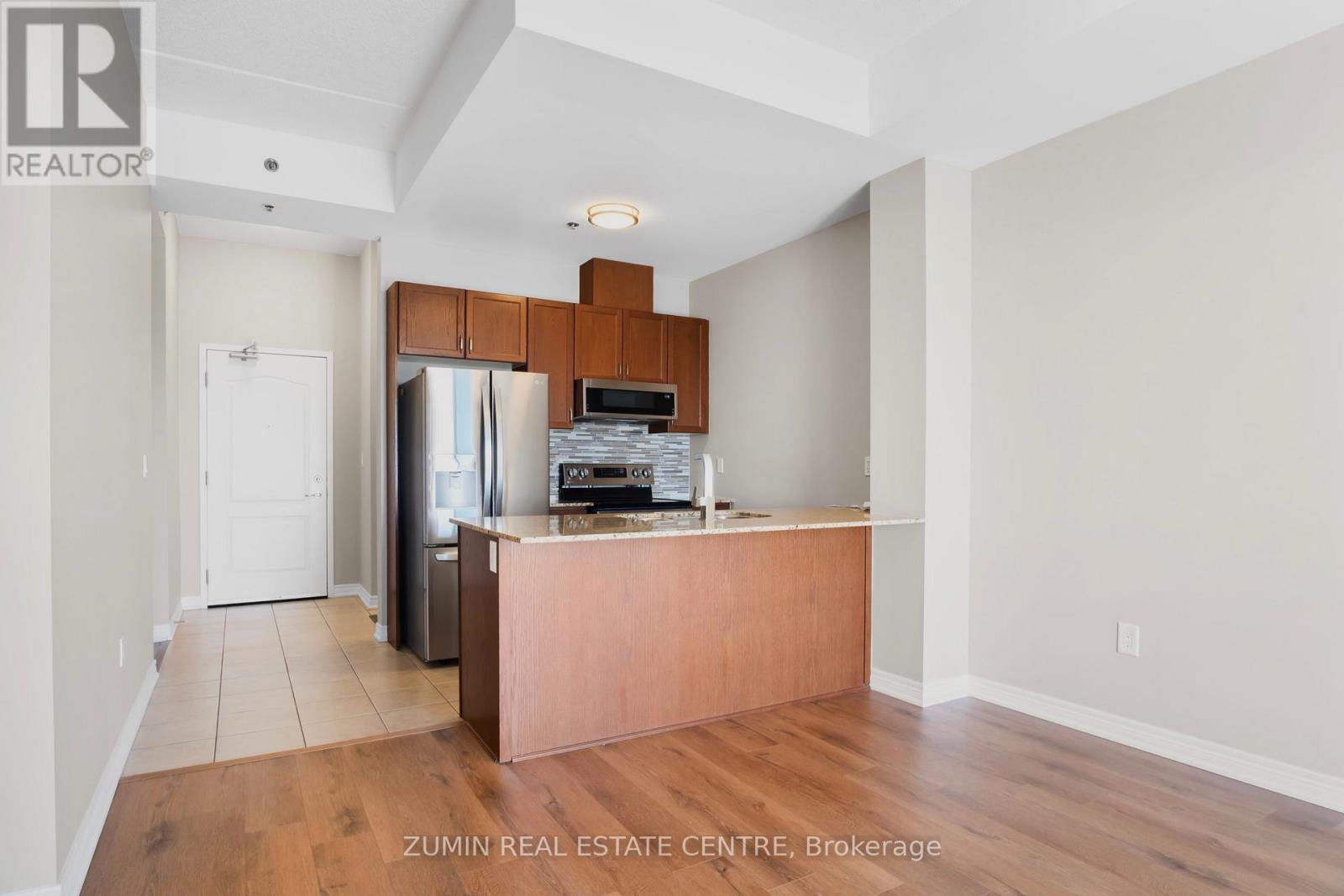A kitchen area with a refrigerator, microwave, and oven.