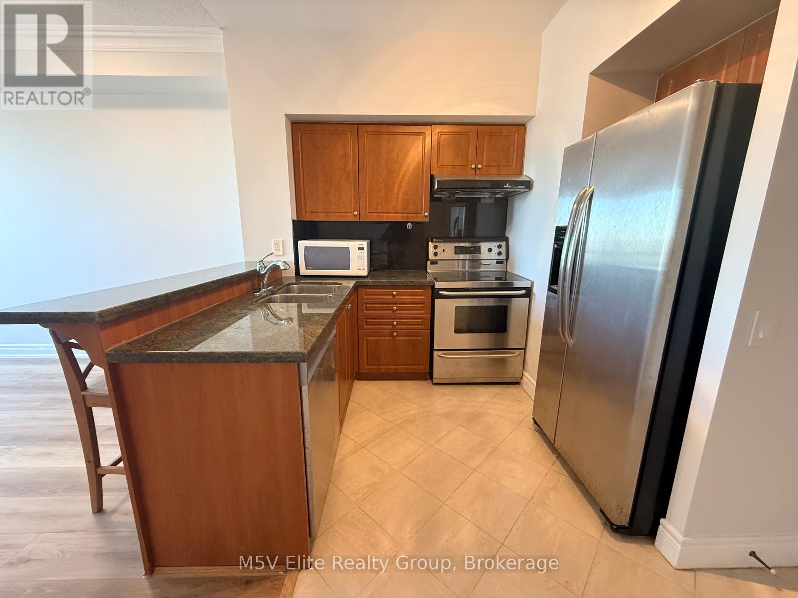 A kitchen with a refrigerator, microwave, and oven.