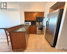 A kitchen with a refrigerator, microwave, and oven.