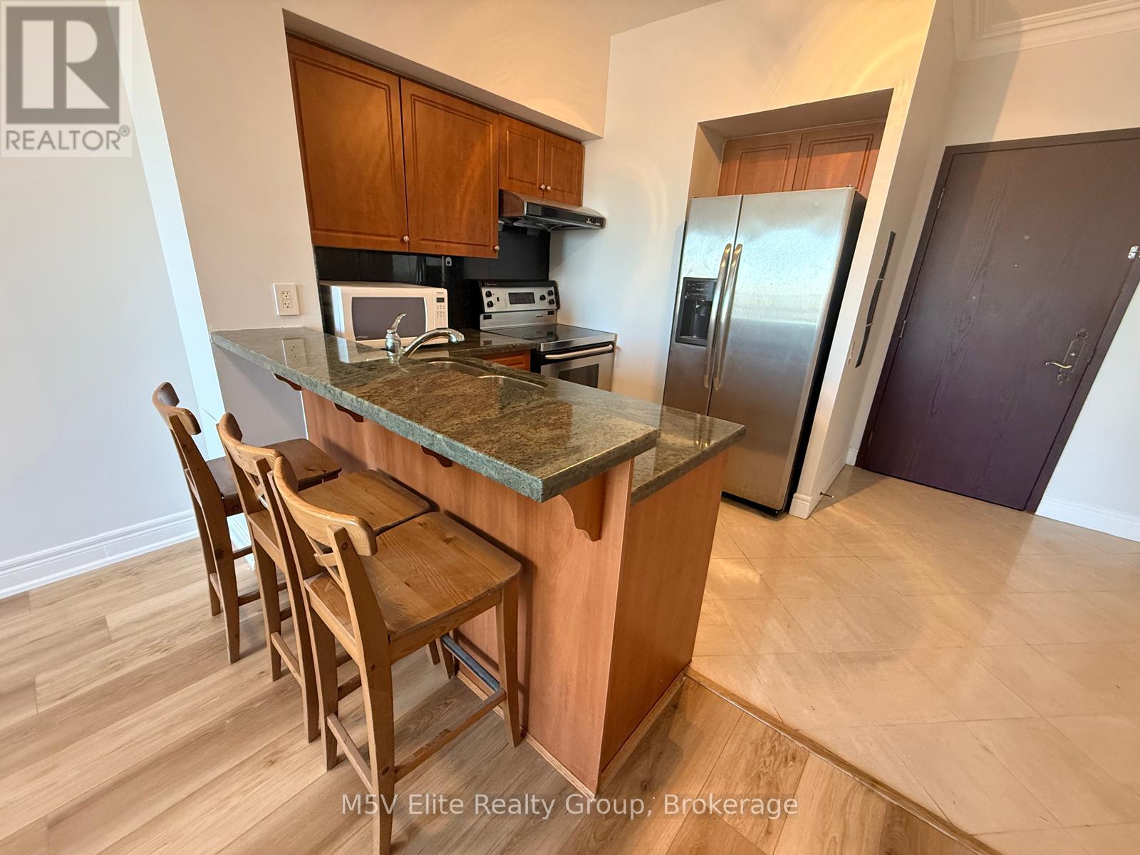A kitchen with a table and chairs in front of a refrigerator.