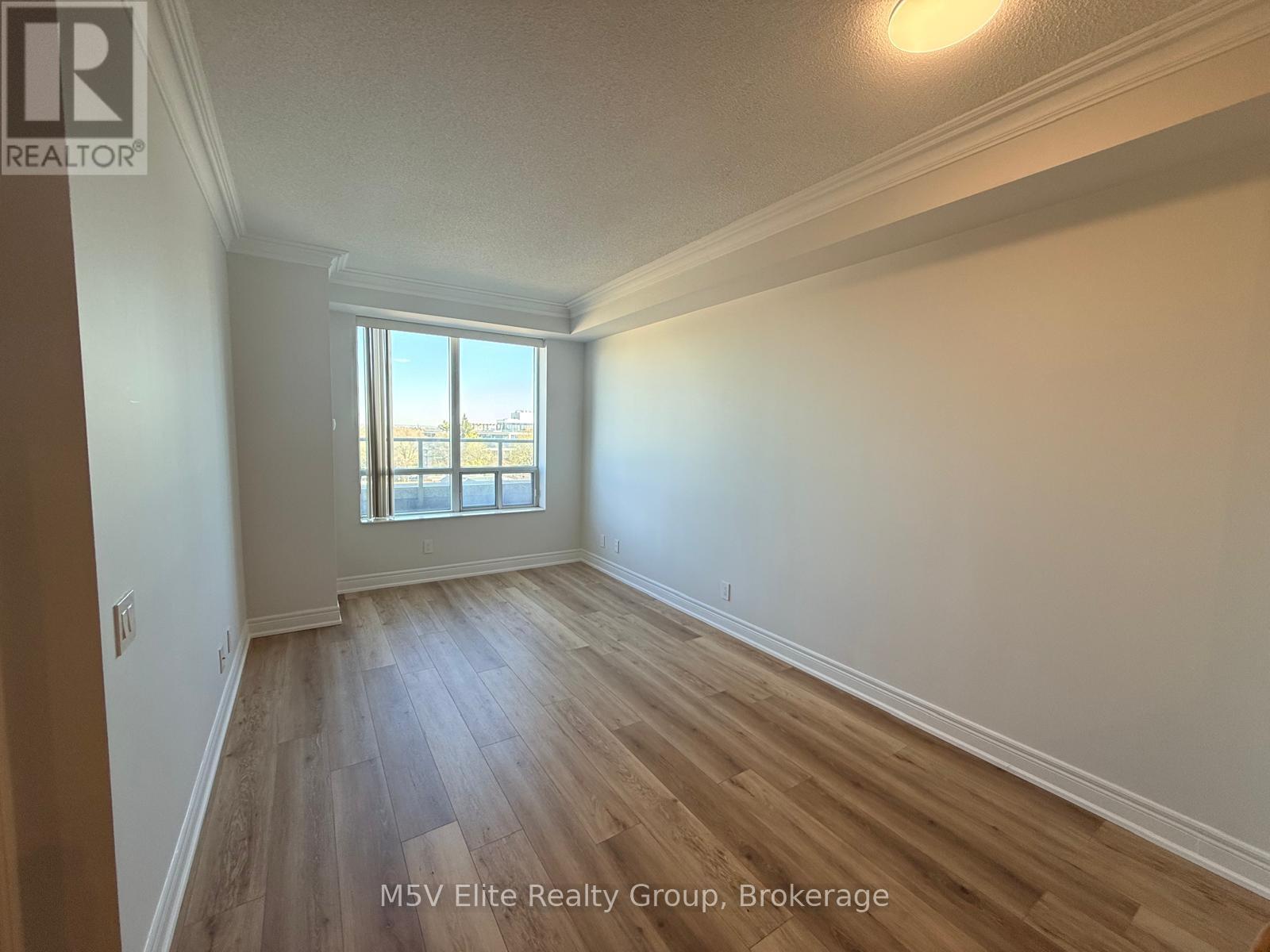 A room with wooden flooring and a window overlooking a balcony.
