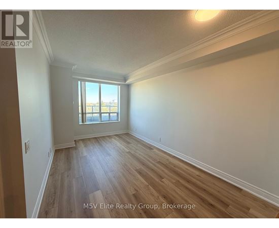 A room with wooden flooring and a window overlooking a balcony.