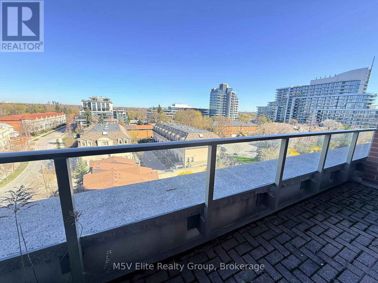 A view from a balcony overlooking a cityscape with buildings and a clear sky.