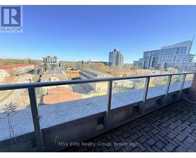 A view from a balcony overlooking a cityscape with buildings and a clear sky.