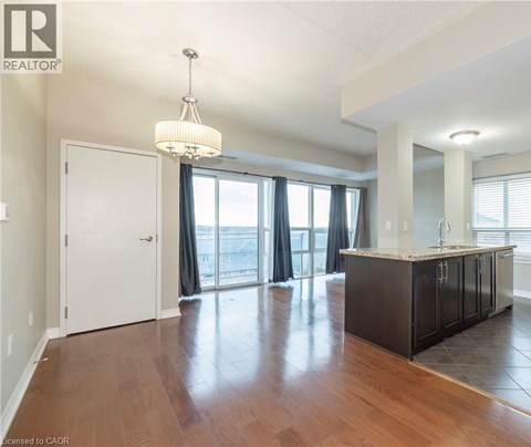 A well-lit, spacious kitchen and living room with hardwood floors and a large window.