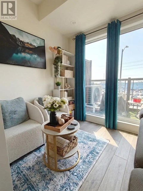 A living room with a white couch, a wooden table with a vase of flowers, and a large window with blue curtains.