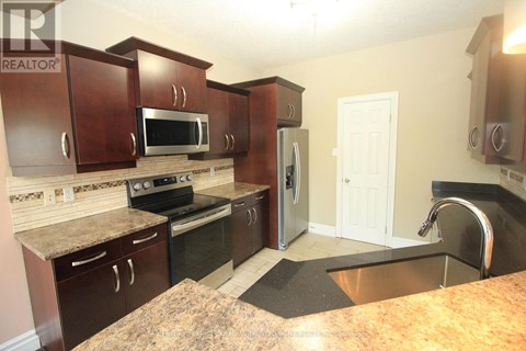 A kitchen with brown cabinets and a granite counter top.