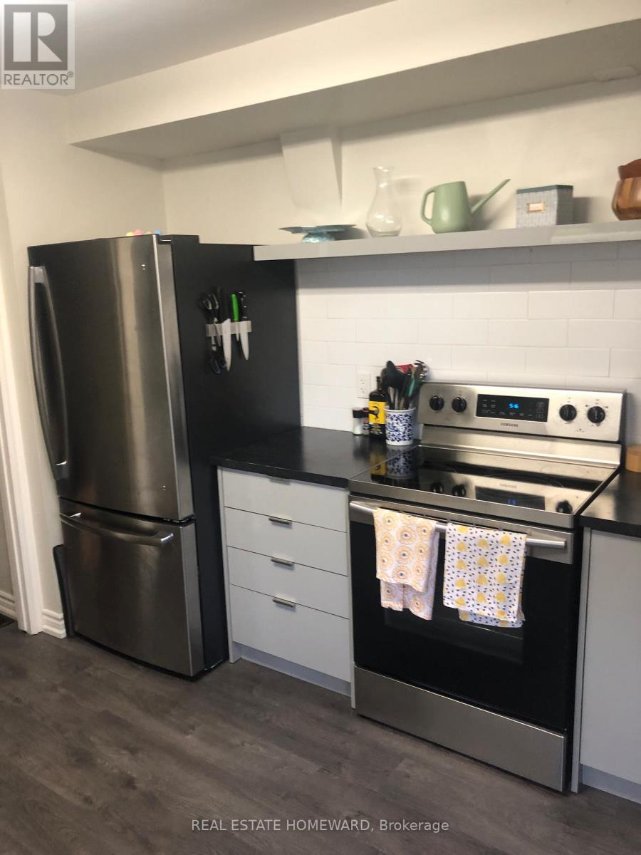 A modern kitchen with a black fridge and stove top oven.
