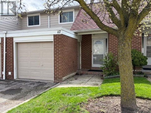 A house with a garage door and a tree in front.