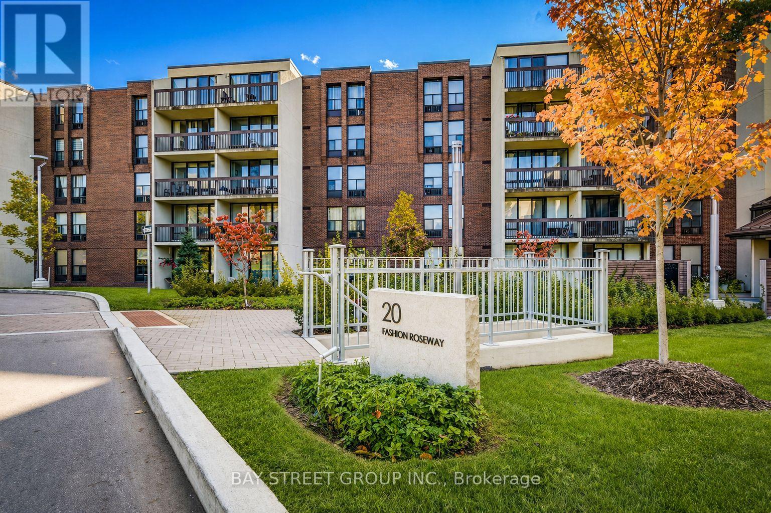 A street view of a residential area with apartment buildings and a sign that reads "20 BAY STREET GROUP INC. Brokerage".