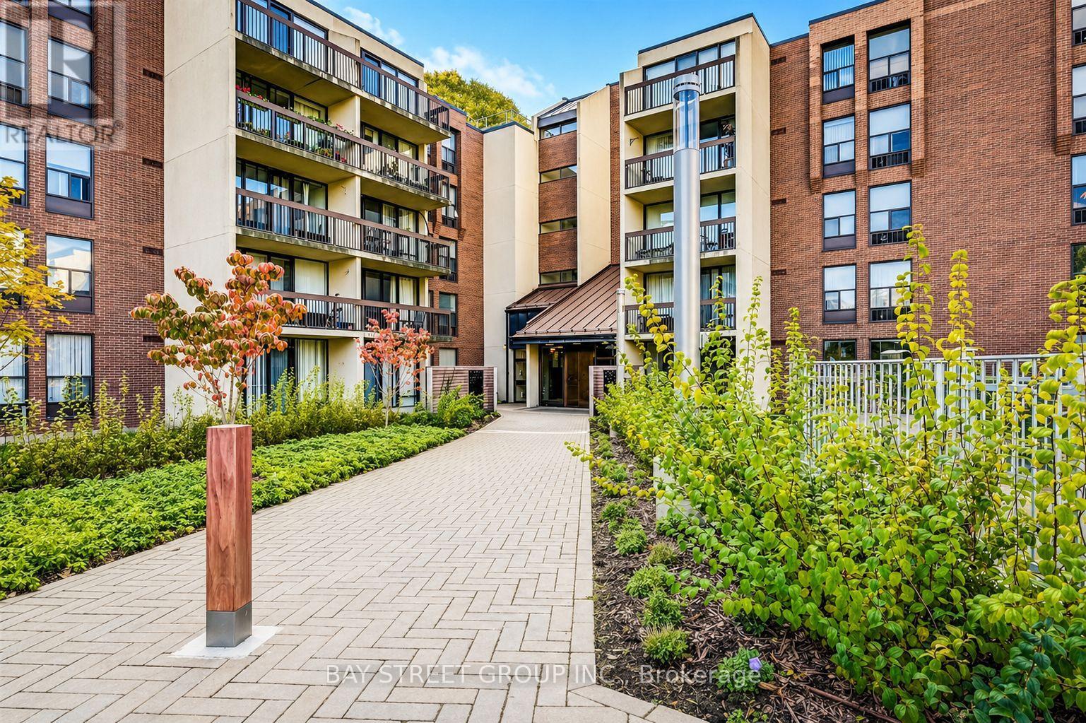 A brick building with a balcony and a small garden in front.