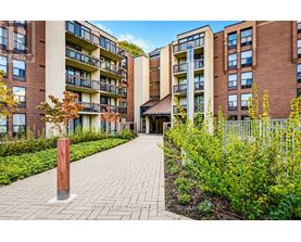 A brick building with a balcony and a small garden in front.