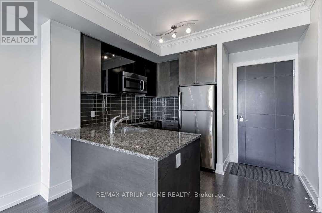 A modern kitchen with a granite countertop and stainless steel appliances.