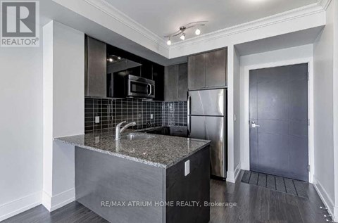 A modern kitchen with a granite countertop and stainless steel appliances.