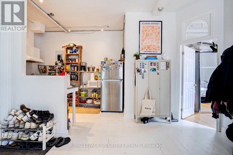 A kitchen with a refrigerator and a pile of shoes.