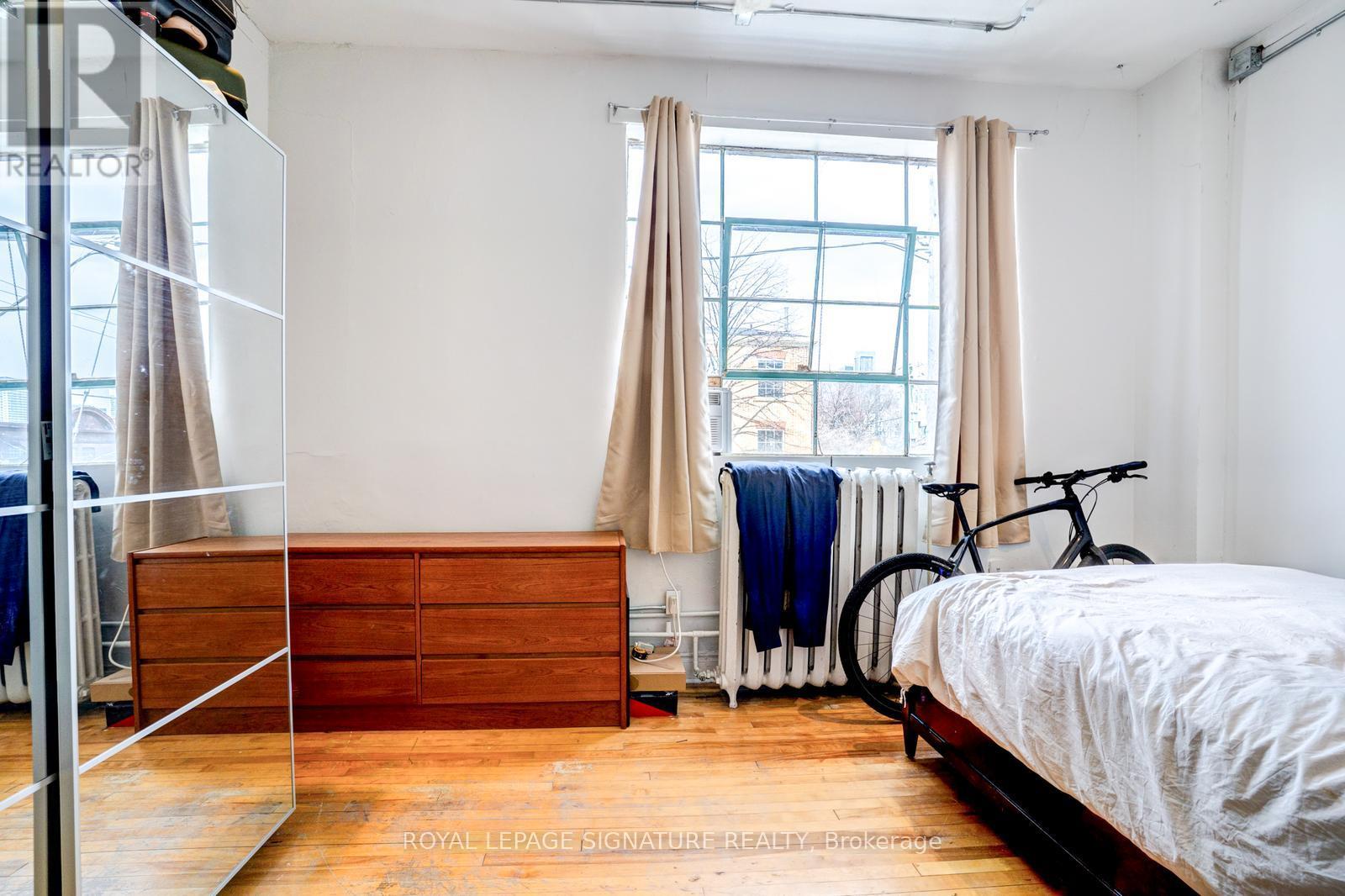 A bedroom with a bed, a dresser, and a bicycle.