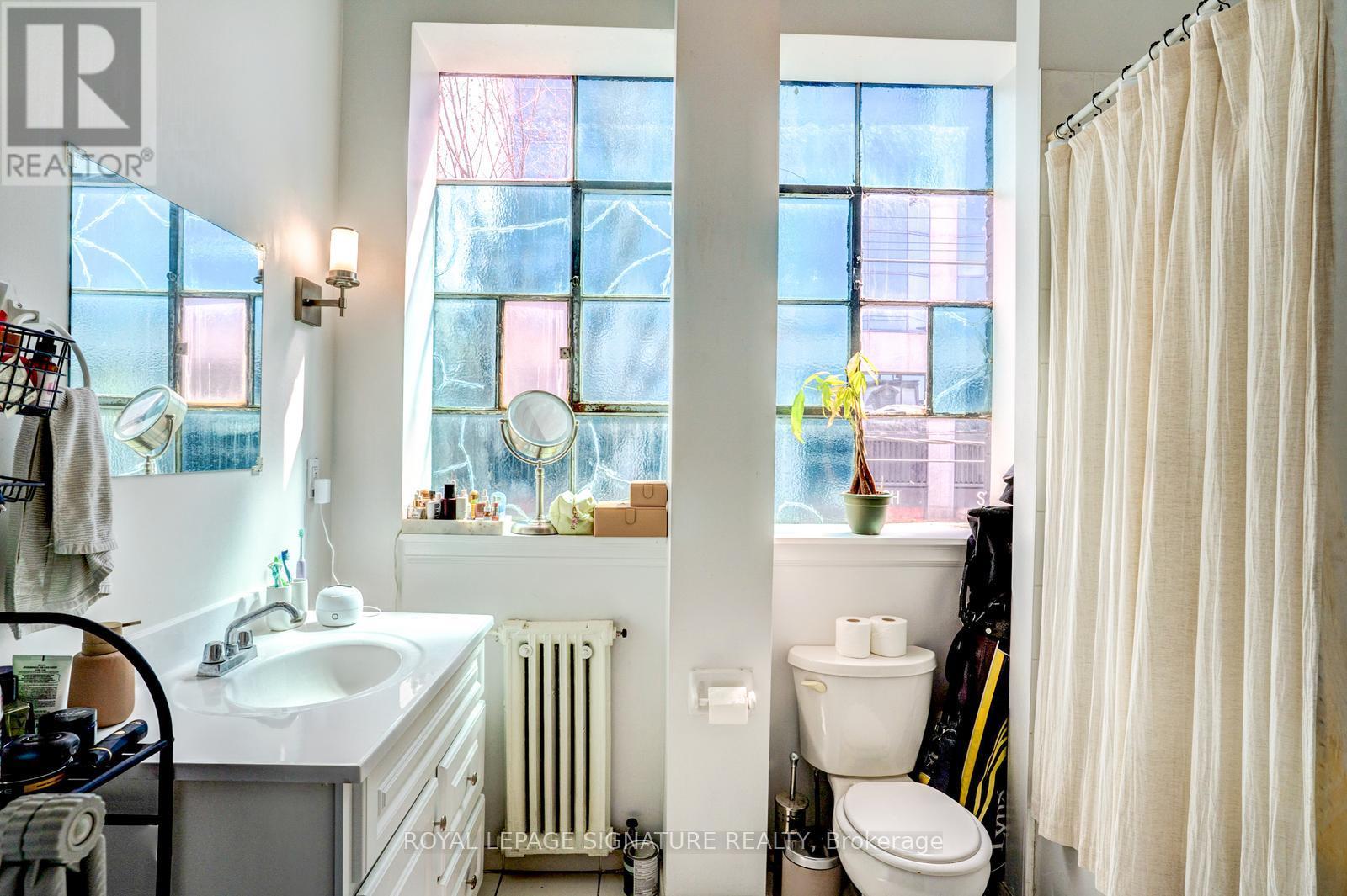 A bathroom with a white sink and a window with a view of a building.