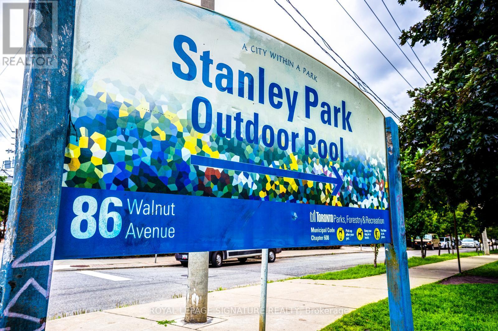 A sign for Stanley Park Outdoor Pool is displayed on a pole.