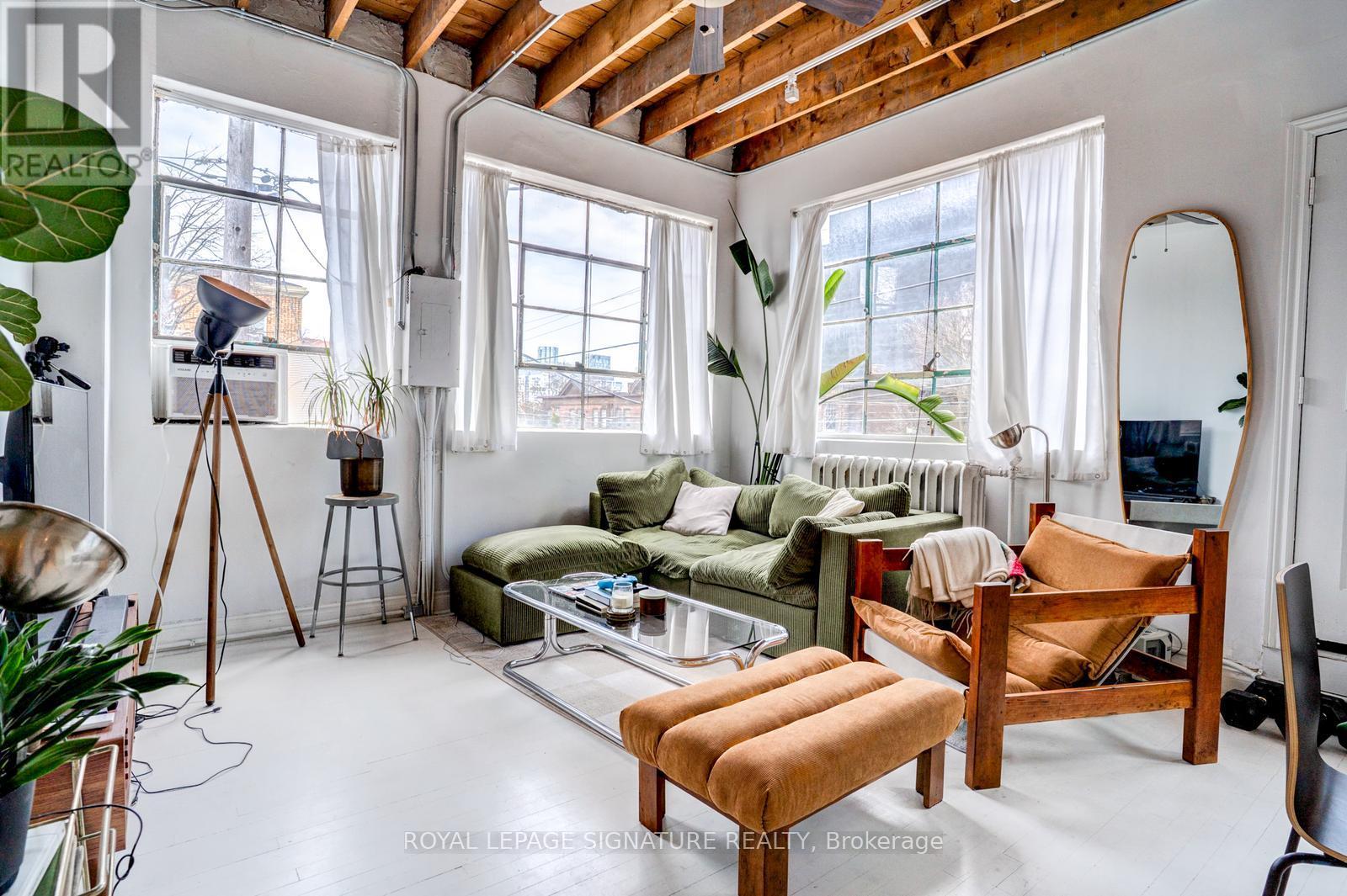 A well-lit, spacious living room with a large window, a sofa, a coffee table, and a chair.