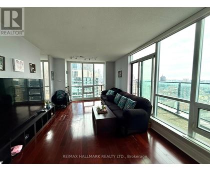 A living room with a black couch and a wooden floor.