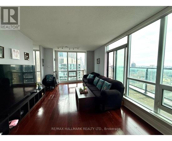 A living room with a black couch and a wooden floor.