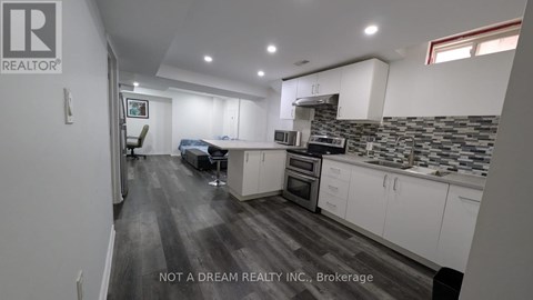 A modern kitchen with white cabinets and a grey floor.