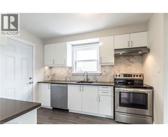 A kitchen with white cabinets and a marble backsplash.