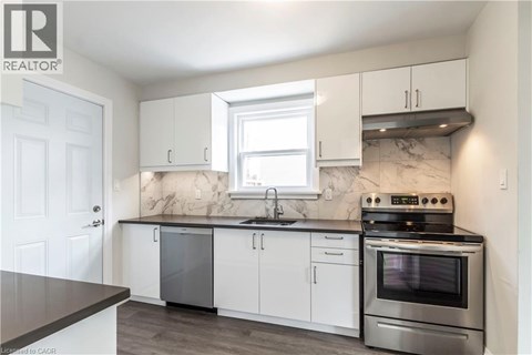 A kitchen with white cabinets and a marble backsplash.