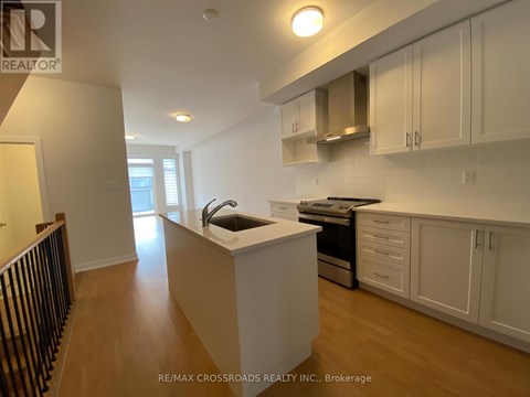 A kitchen with white cabinets and a black railing.