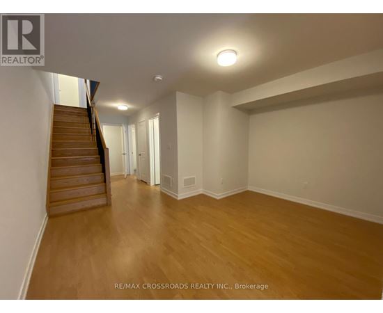 A spacious room with wooden floors and a staircase leading to another level.