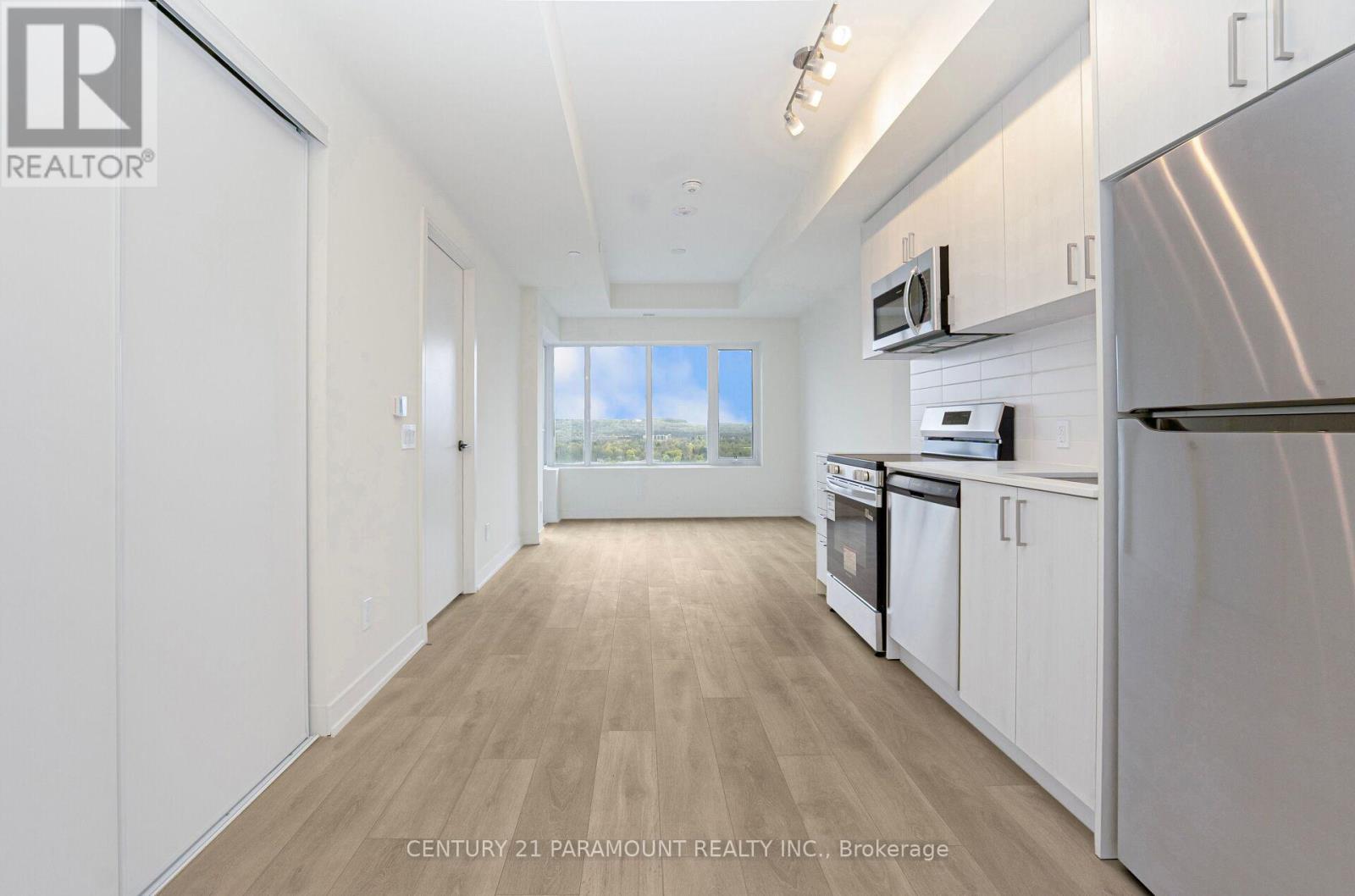 A kitchen with white cabinets and a stainless steel refrigerator.