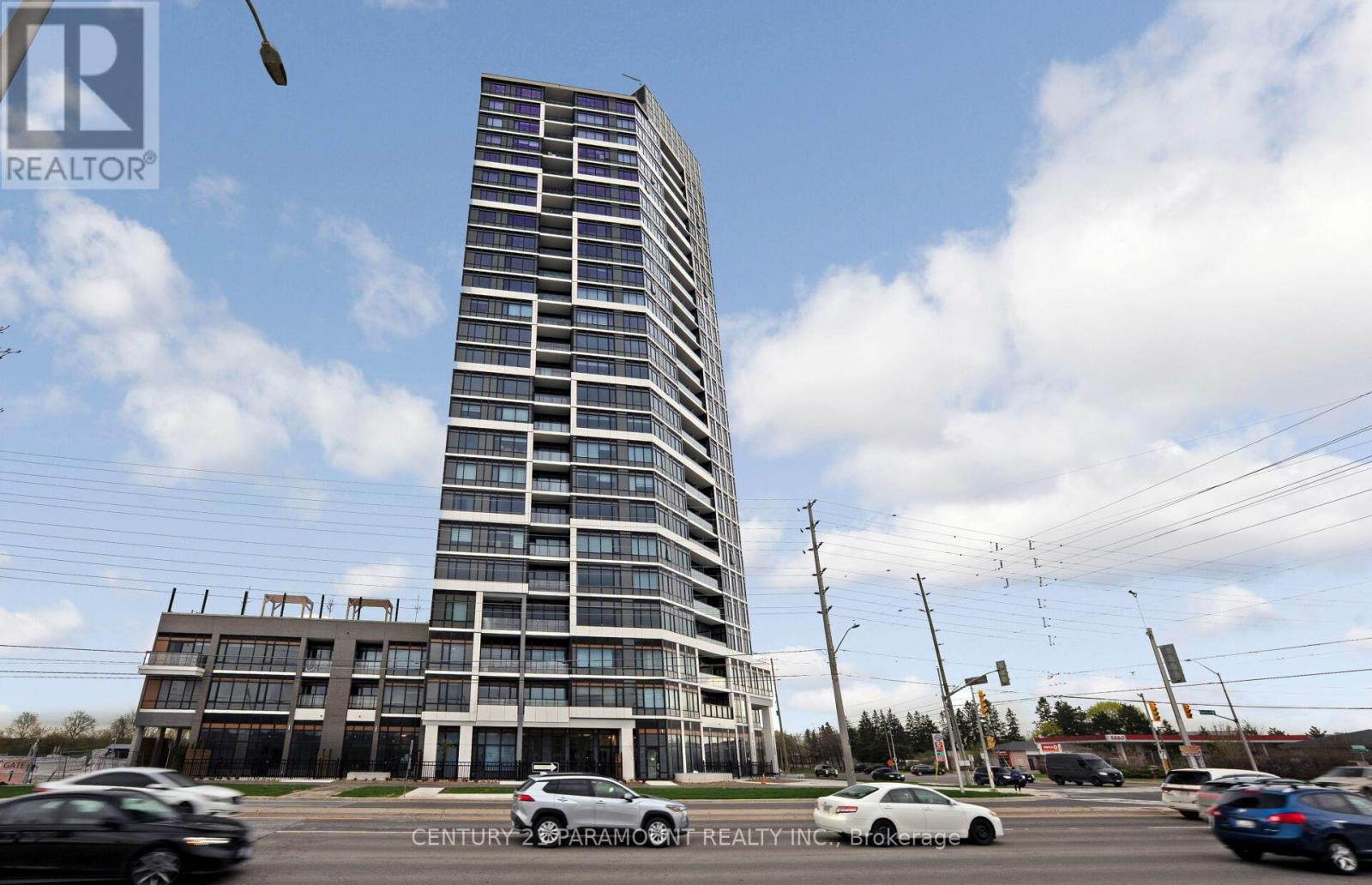 A tall building with many windows is under construction with a car parked in front of it.