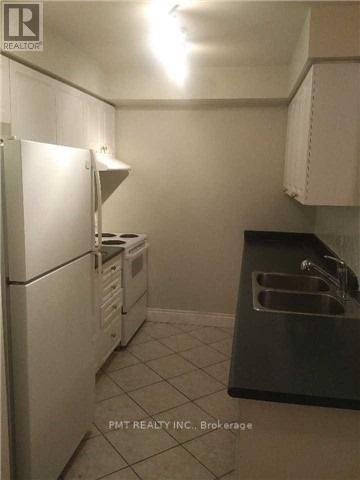 A kitchen with a white fridge and a black counter top.
