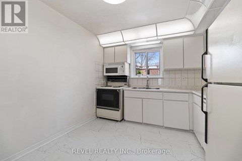 A kitchen with white cabinets and a window.