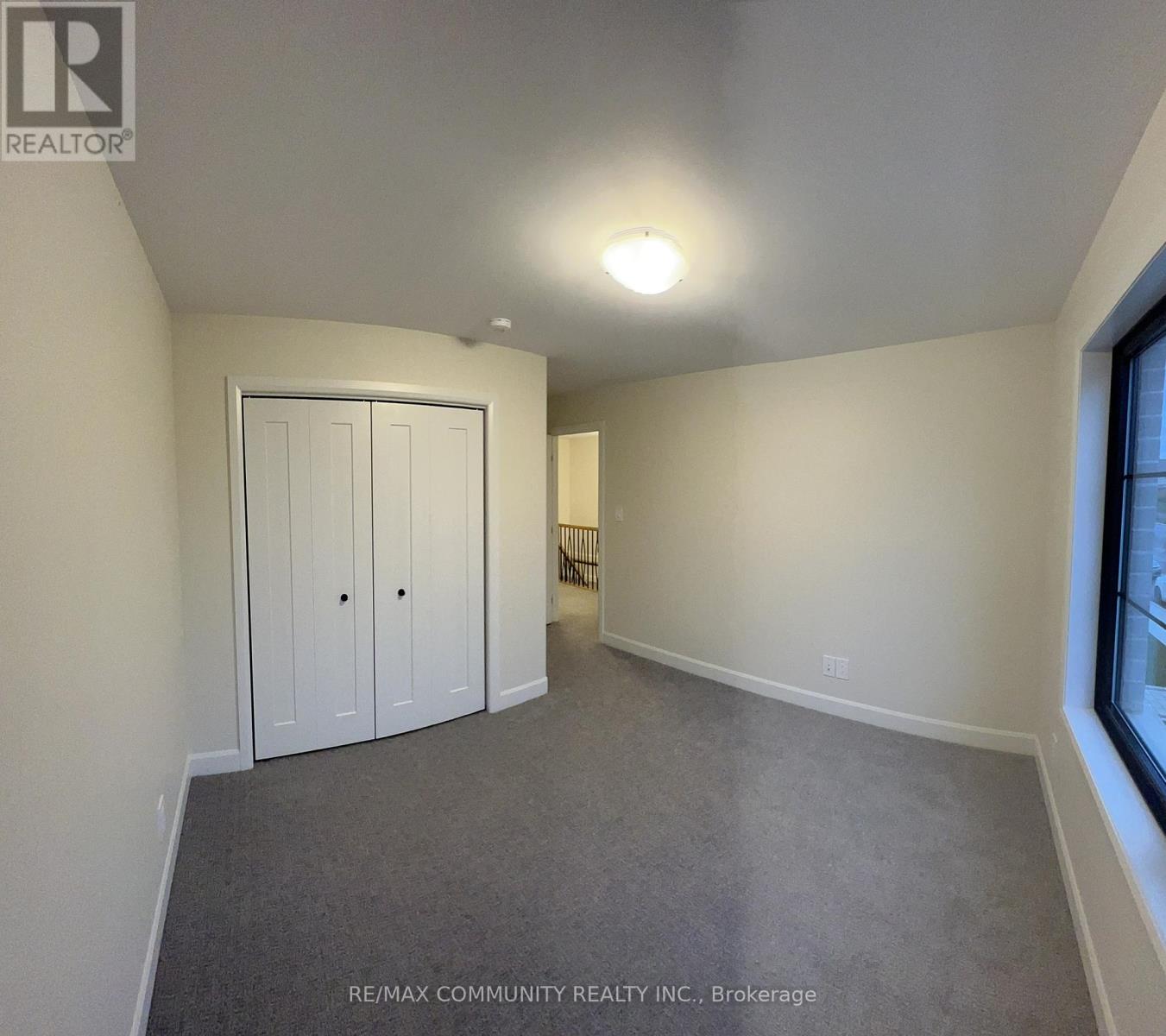 A bedroom with a white door and a grey carpet.